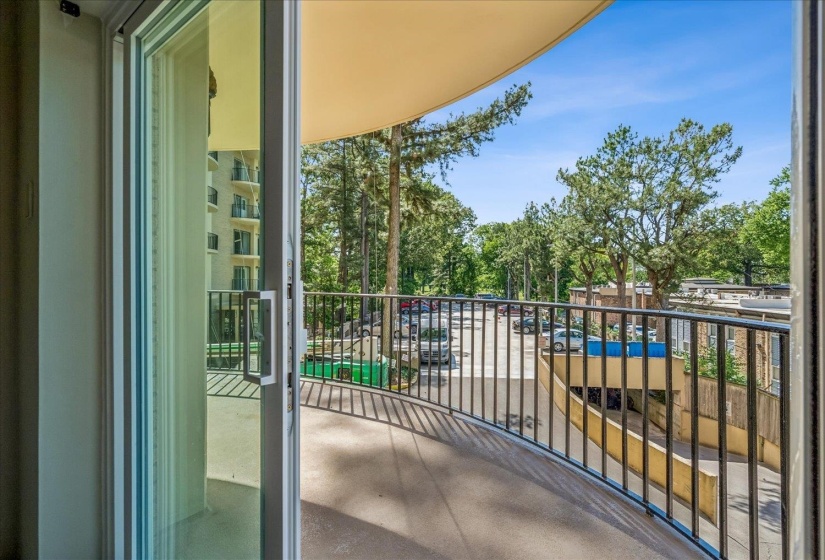 Curved balcony featuring a black metal railing, concrete flooring, and a sliding glass door