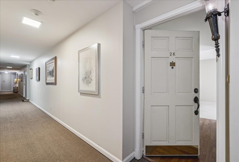 Entry door featuring panel detailing, dark-finish hardware, and a wall-mounted sconce