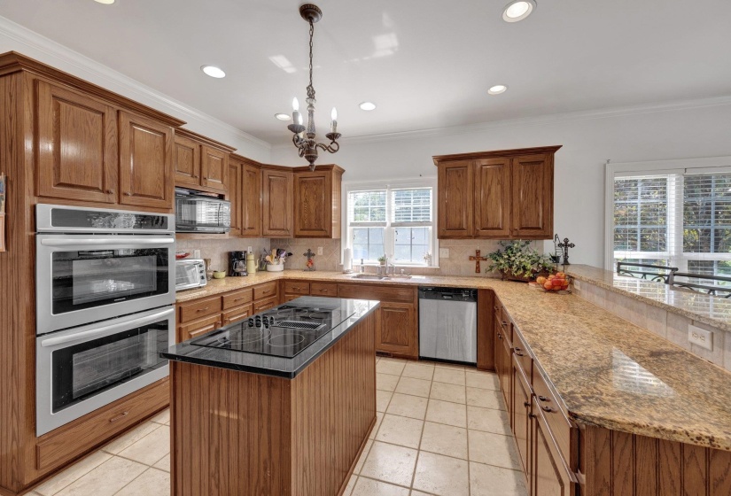 Kitchen featuring wood cabinetry, light granite countertops, recessed lighting, double wall ovens, and a center island with a cooktop
