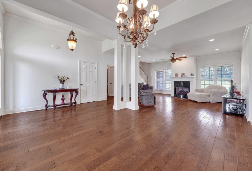 Spacious open-concept living area featuring wood-finish flooring, a decorative chandelier, and recessed lighting