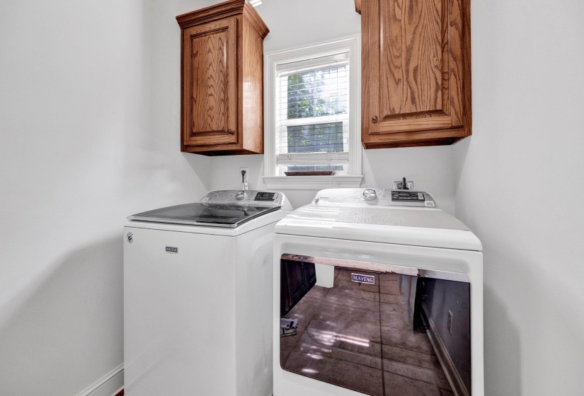 Laundry area featuring white walls, wood-finish cabinetry, and a window with blinds