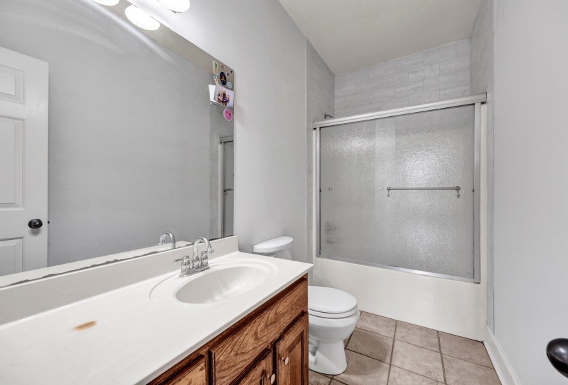 Bathroom featuring a wood-finish vanity with a white countertop, an integrated sink, and a chrome faucet