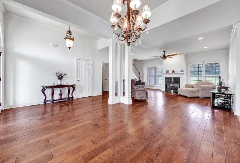 Expansive interior featuring wood-finish flooring, a decorative chandelier, recessed lighting, a fireplace with a mantel, and large windows