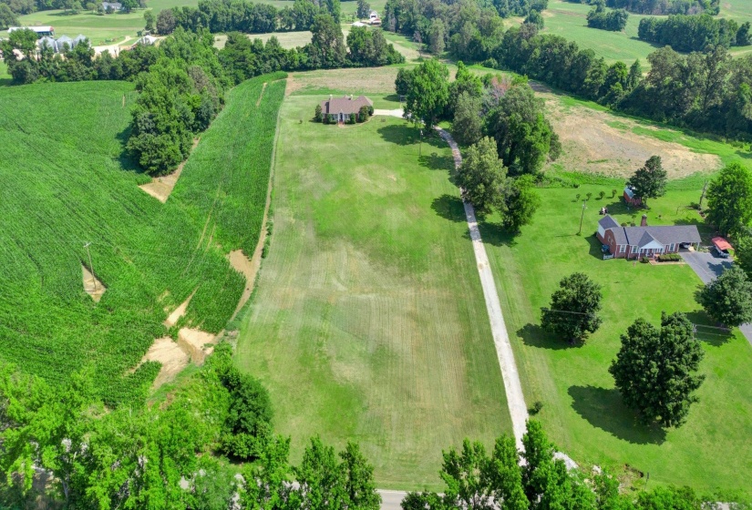 Extensive property with a long driveway, expansive grassy areas, and mature trees