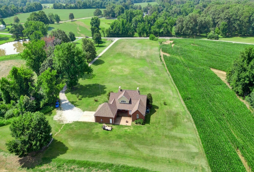 Expansive property featuring a brick residence with a multi-gabled roof, surrounded by extensive green lawns
