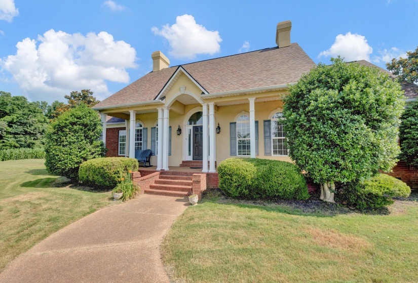 Stucco and brick exterior with a columned front porch and brick steps