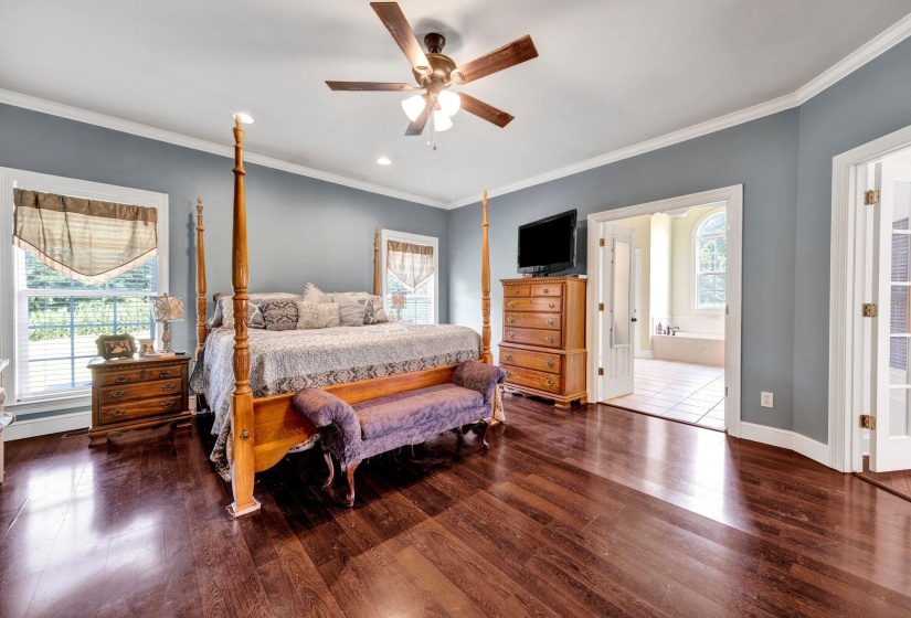 Spacious bedroom featuring wood-finish flooring, light blue walls, and white crown molding