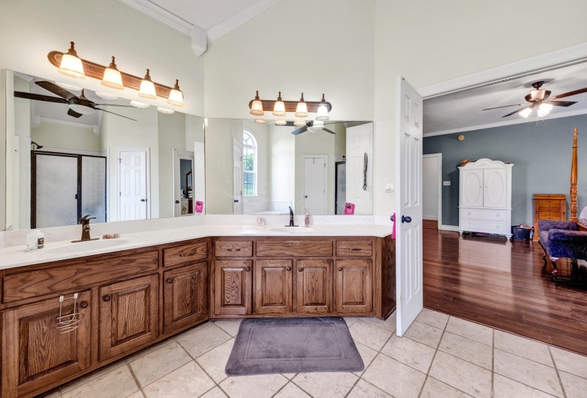 Dual vanity with wood cabinetry, white countertops, and bronze fixtures
