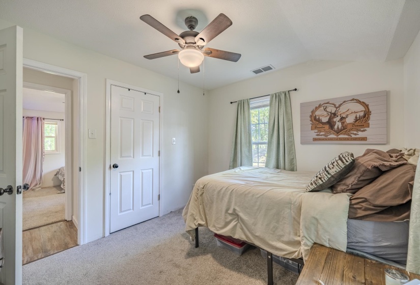 Carpeted room featuring a ceiling fan with integrated lighting, a window with curtains, and an interior door with a paneled design