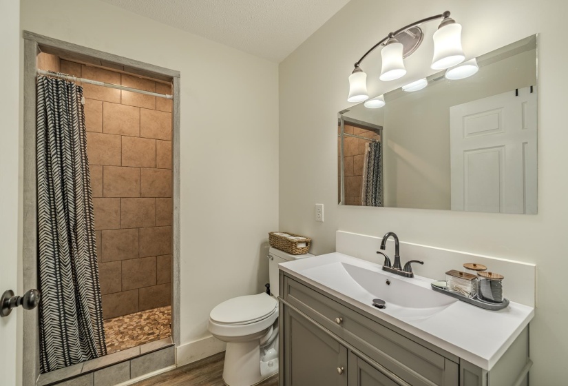 Bathroom featuring a walk-in shower with brown tile surround and river rock flooring
