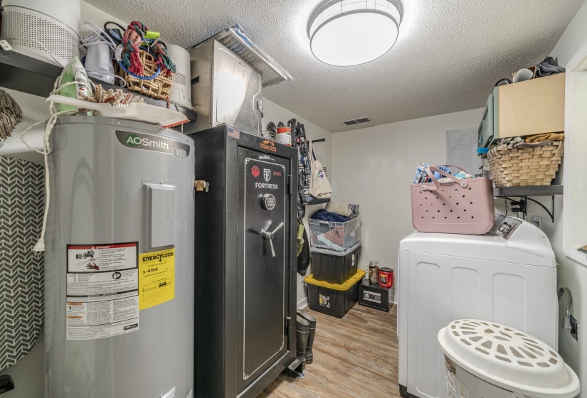 Dedicated utility space featuring wood-finish flooring, a contemporary flush-mount ceiling light, and wall-mounted shelving for storage