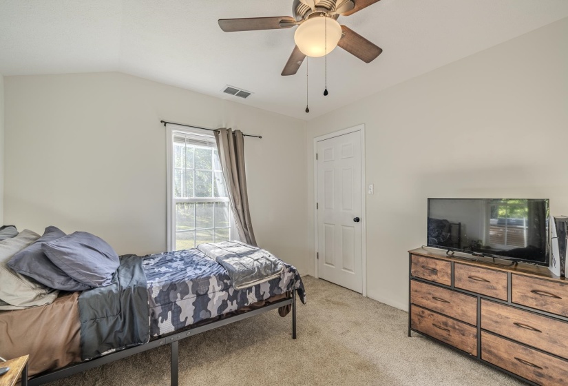 Vaulted ceiling with a ceiling fan and light fixture, a window with exterior views, light-colored walls, and neutral carpet flooring