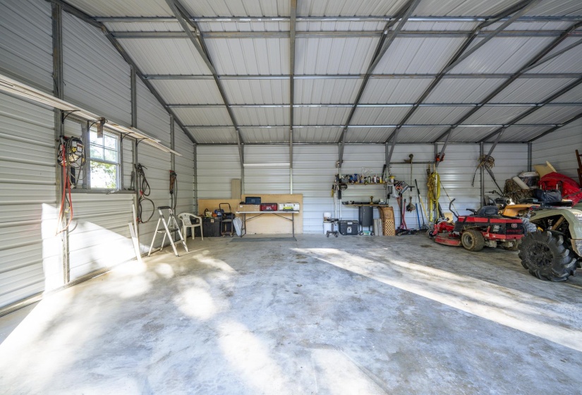 Spacious metal structure featuring a concrete floor, high vaulted ceiling, and multiple windows providing natural illumination