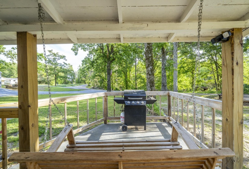 Covered porch featuring a wooden porch swing, exposed wood support beams, and a wood railing