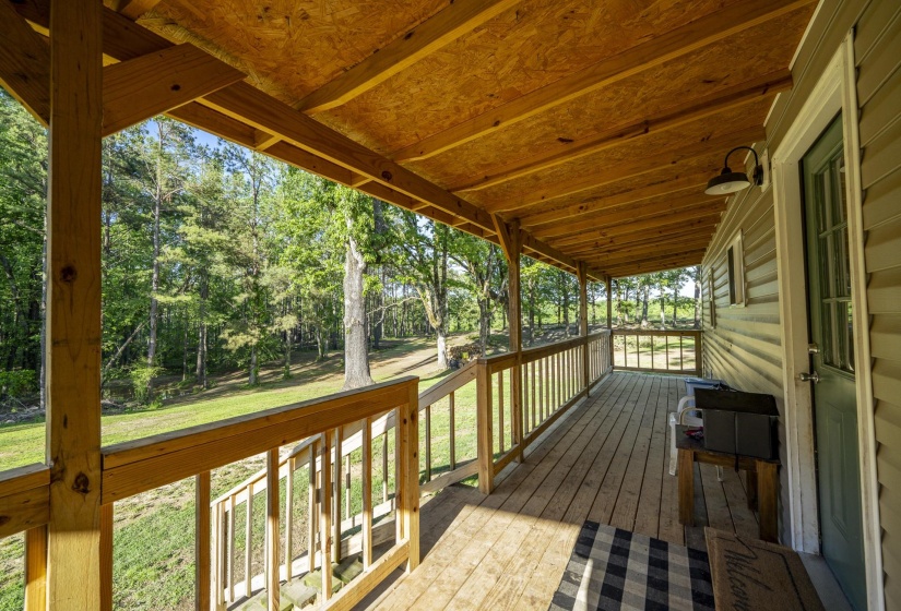 Expansive covered porch featuring wood decking and railings