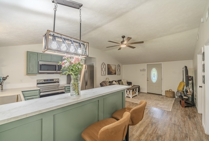Open concept living area with vaulted ceilings and wood-finish flooring