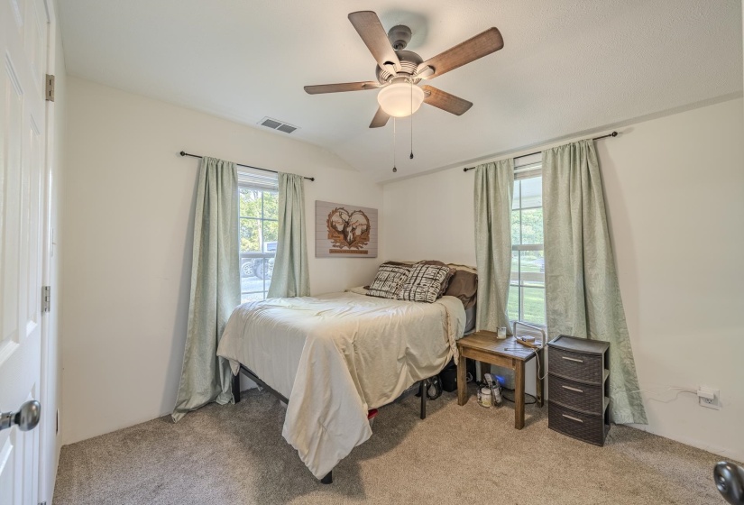 Carpeted room featuring a ceiling fan with light, two windows, and a white paneled door