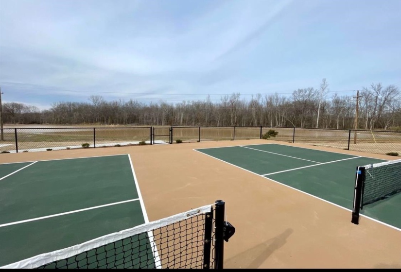 View of tennis court with fence and community basketball court
