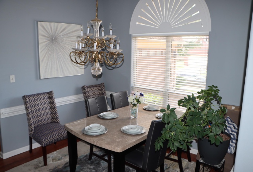 Dining area featuring a prominent chandelier and a large window with horizontal blinds