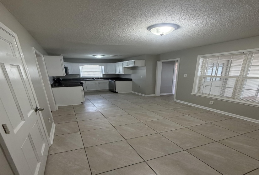 Kitchen and dining area featuring tile flooring, white cabinetry, dark countertops, and a double window with blinds