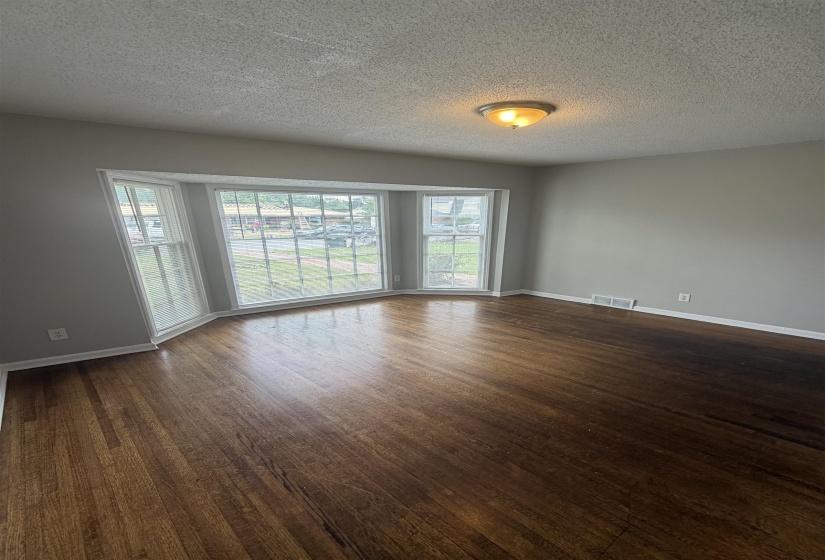 Bay window with multiple panes, wood-finish flooring, a neutral wall color, and white baseboards