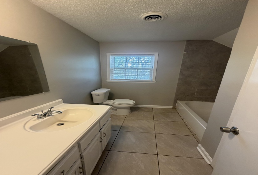 Bathroom featuring a single vanity with an integrated sink, chrome faucet, and white cabinetry