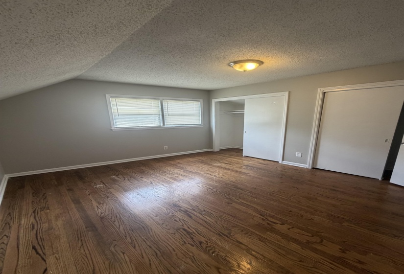 Room featuring rich wood-finish flooring, light gray wall paint, and a textured ceiling