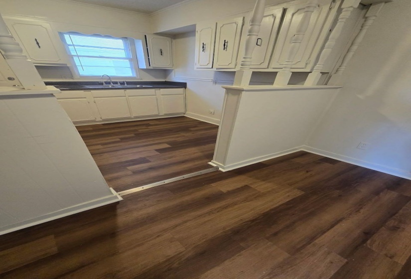 Efficient kitchen space featuring wood-finish flooring, white cabinetry, dark countertops, and a stainless steel sink with a single-handle faucet