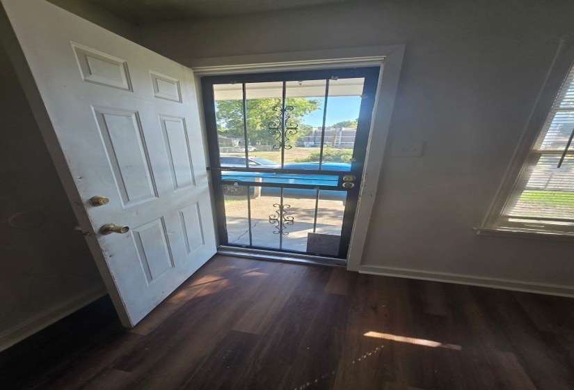 Entryway featuring wood-finish flooring, a white paneled door, and a security screen door with decorative wrought iron accents