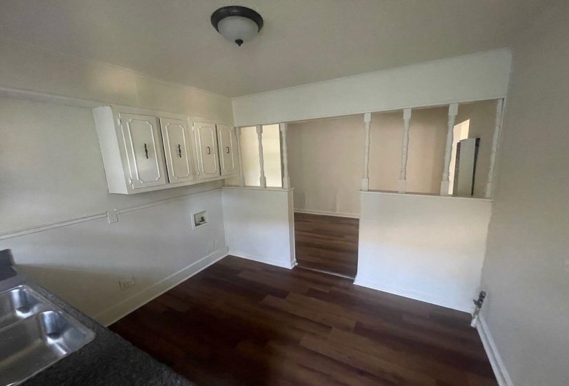 Kitchen area featuring wood-finish flooring, white cabinetry, a double basin stainless steel sink, and a semi-flush mount ceiling light