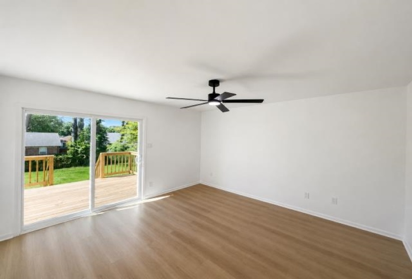 Bright room featuring wood-finish flooring, a modern black ceiling fan, and white walls