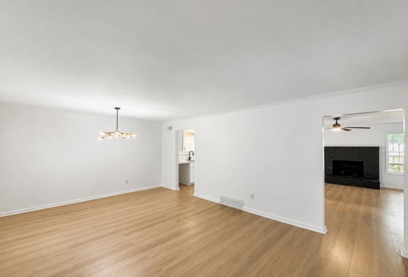 Spacious interior featuring light wood-finish flooring, white walls, and a modern chandelier
