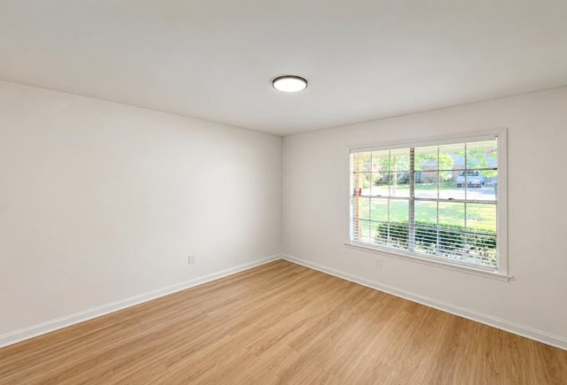 Room featuring wood-finish flooring, white baseboards, and a single window with blinds