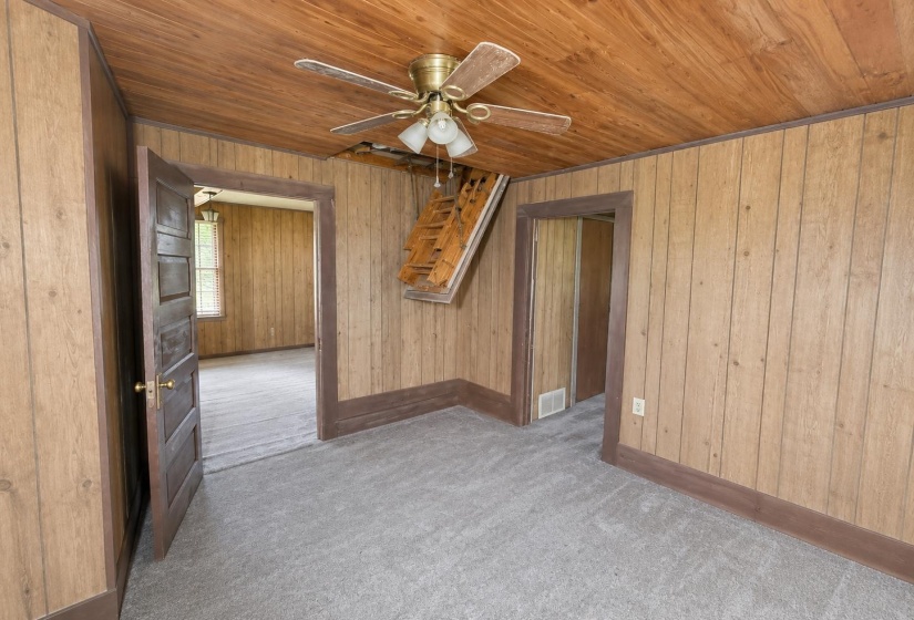 Room with wood-panel walls and ceiling, featuring a brass-finish ceiling fan with integrated lighting