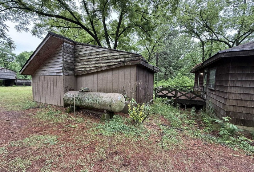 Exterior structure with wood siding and a pitched roof, featuring surrounding mature trees