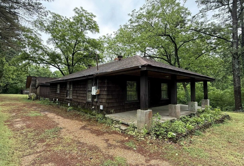 Wood-shingle exterior with a covered front porch featuring square support columns and a concrete floor