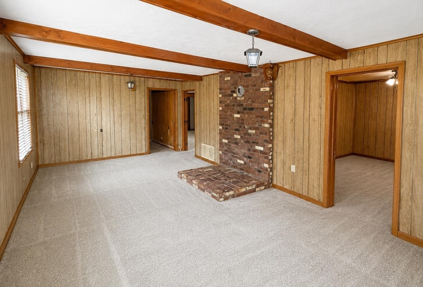 Spacious room featuring exposed ceiling beams and light-toned carpeting