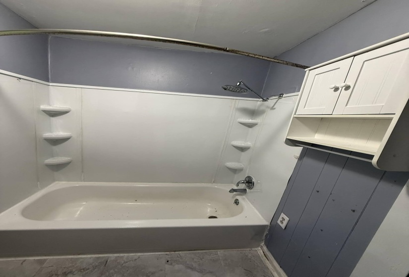 White bathtub and shower surround with integrated shelving