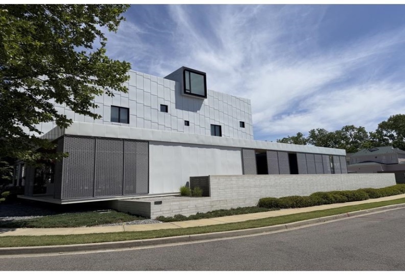 Modern architectural exterior featuring a prominent cantilevered window and varied facade materials