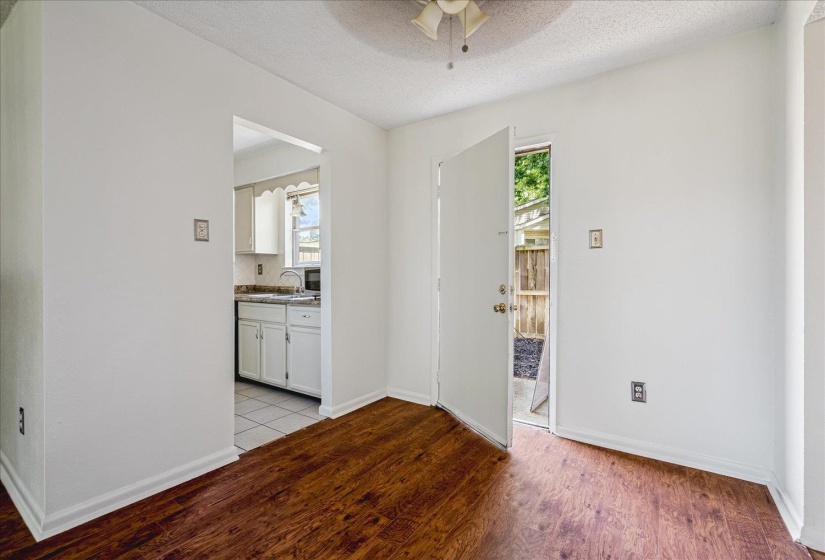 Interior room featuring wood-finish flooring, white walls, and a white ceiling with a ceiling fan