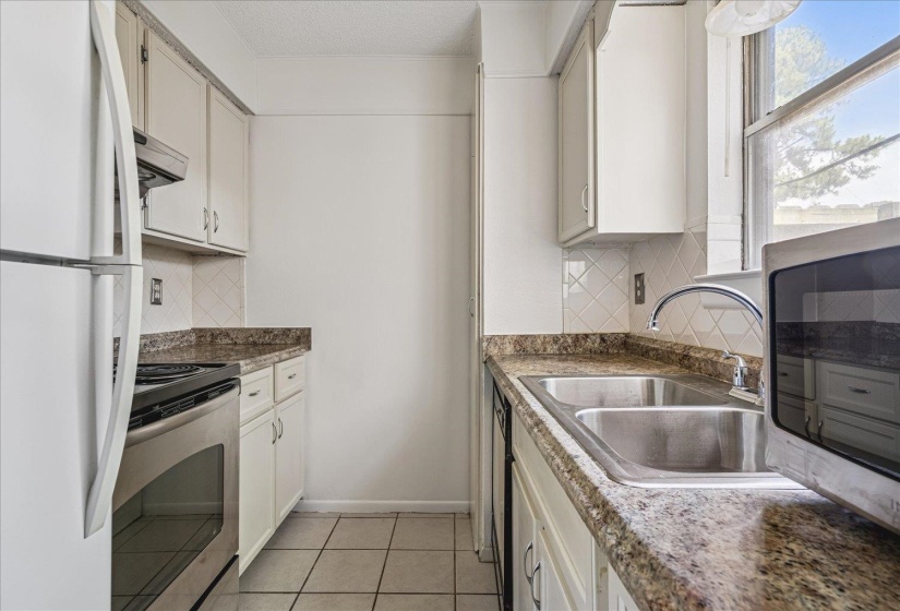 Kitchen featuring white cabinetry, stone-finish countertops, and a dual basin stainless steel sink