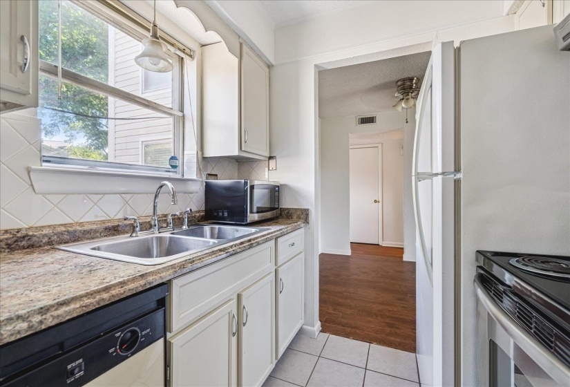 Kitchen featuring white cabinetry, a double basin stainless steel sink, a black dishwasher, and a white refrigerator
