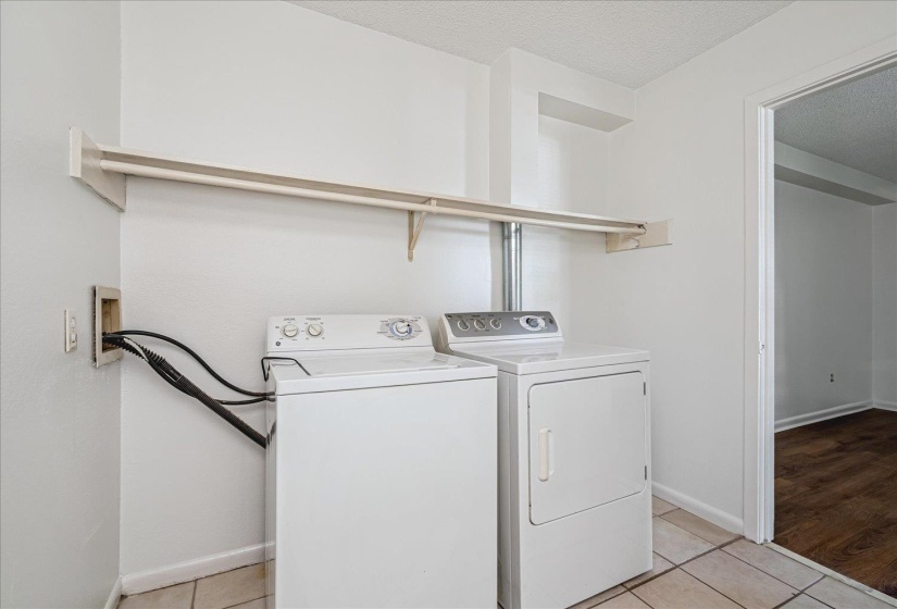 Dedicated laundry area featuring a washer and dryer, an overhead clothes rod, and tile flooring