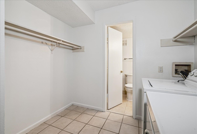 Laundry area featuring tile flooring, built-in shelving, a clothes hanging rod, and white painted walls