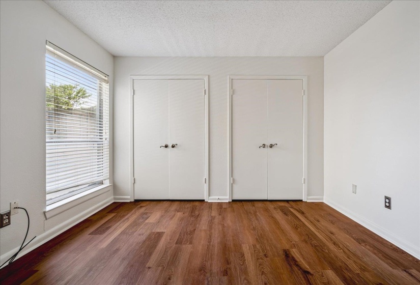 Interior room featuring warm wood-finish flooring, crisp white walls, and two sets of bi-fold doors