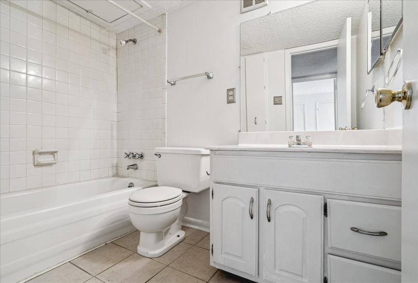 Bathroom featuring a white vanity with cabinet storage, a built-in sink, and an expansive wall mirror