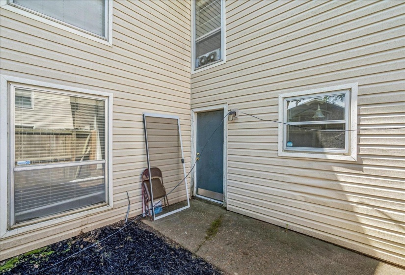 Exterior wall featuring beige horizontal siding, multiple windows, and a dark entry door