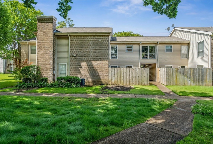 Townhome exterior with brick and horizontal siding, featuring a wood privacy fence and mature landscaping