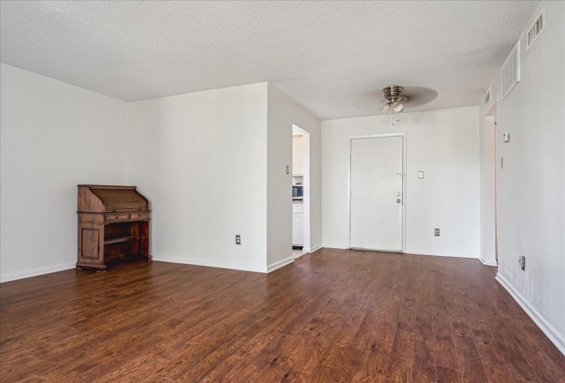 Spacious interior featuring wood-finish flooring, white walls, and a ceiling fan with integrated lighting