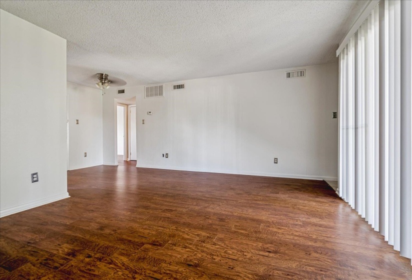 Spacious room featuring wood-finish flooring, white walls, and a textured ceiling